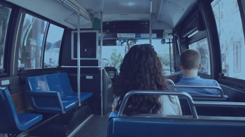 A view from inside a public bus, looking toward the front of the bus with other riders seated in the rows ahead.