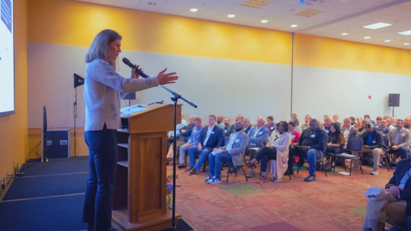 Image of woman speaking on stage at a meeting.