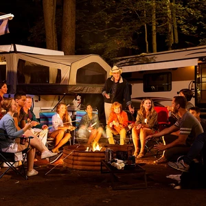 Family enjoying camp fire during camping trip with RVs in background