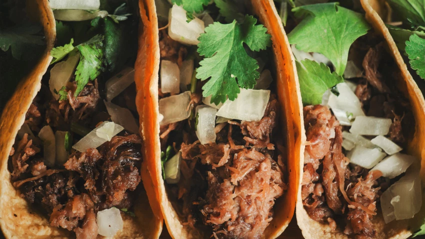 Close-up of four pork tacos with onions and cilantro